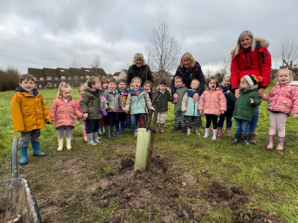 Preschool children plant apple tree at Overton Community Orchard